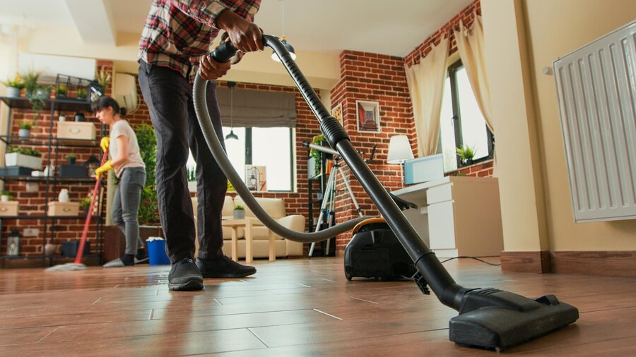 african-american-man-vacuuming-floors-living-room-cleaning-apartment-with-girlfriend-young-adult-using-vacuum-cleaner-woman-wiping-shelves-with-all-purpose-cleaner-tripod-shot_482257-64035