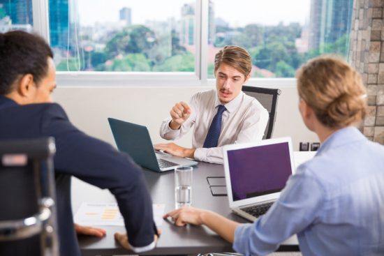 businessman-sitting-with-laptop-talking-other-colleagues (1)