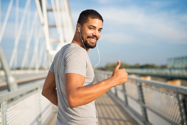 smiling-athlete-with-earphones-holding-thumbs-up-ready-training_342744-650