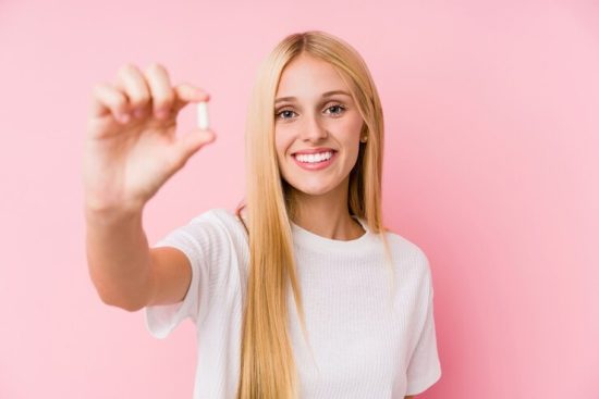 young-blonde-woman-taking-some-pills-isolated-wall_1187-47202