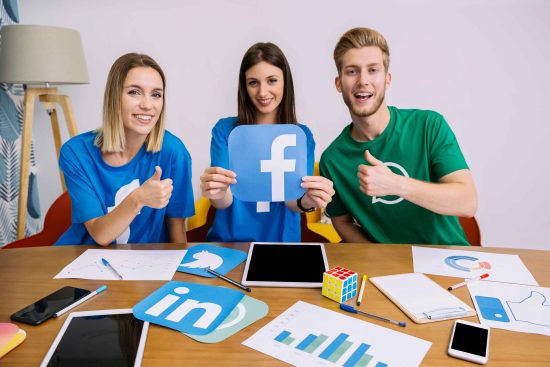 smiling-woman-holding-facebook-logo-with-his-friends-showing-thumbup-sign_11zon