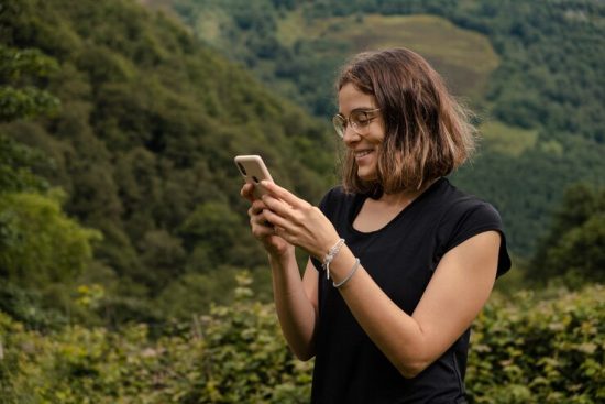 young-woman-using-her-mobile-phone-nature_181624-50060