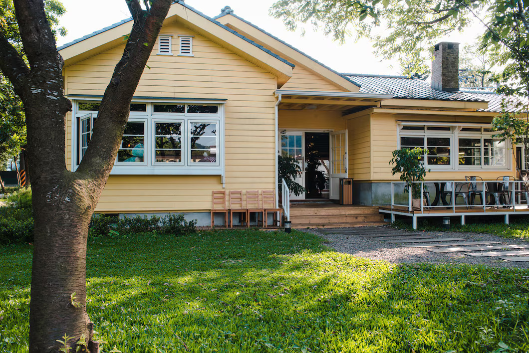 charming-yellow-house-with-wooden-windows-green-grassy-garden_181624-8074